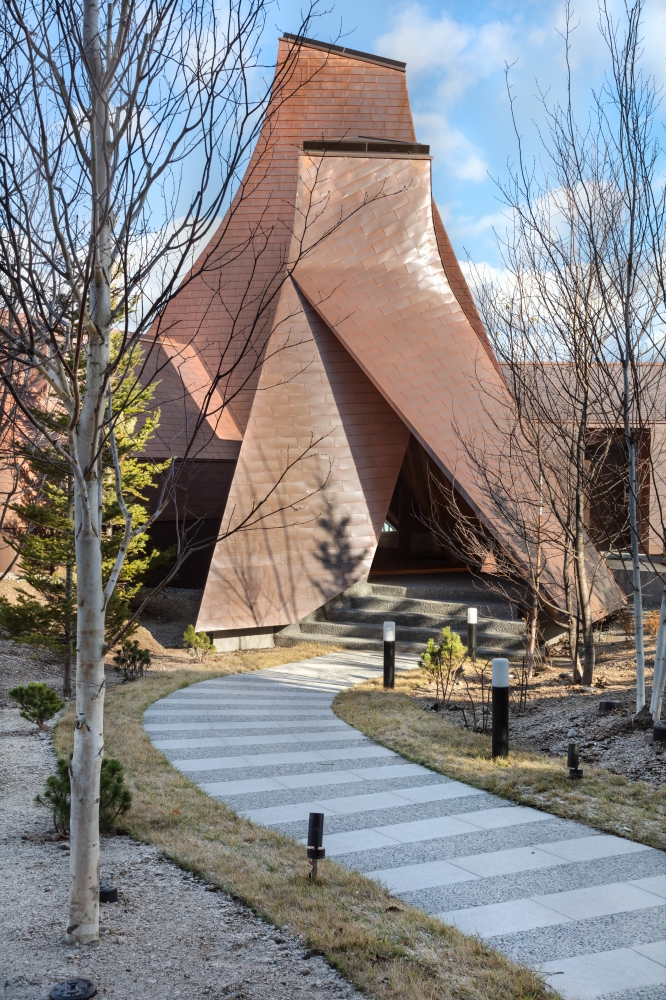 ©Toshihide Kajihara　三角錐の建物群のボリューム は景観に配慮し、温泉がでる場所の周辺を最小限に囲むような佇まいとした。 photo